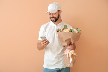 Delivery man with bouquet of flowers and mobile phone on color background