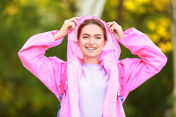 Beautiful young woman wearing raincoat outdoors