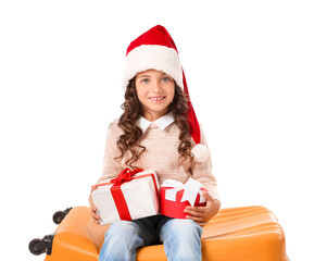 Cute little girl in Santa hat, with luggage and gift boxes on white background. Christmas vacation concept