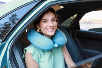 Fototapeta na wymiar Beautiful young woman with travel pillow sitting in car