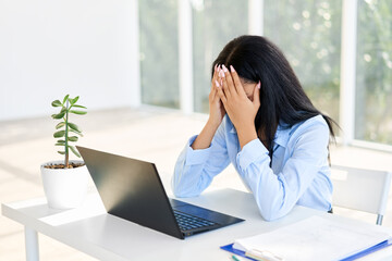 Stressed tired businesswoman closed face by two hands sitting in modern office