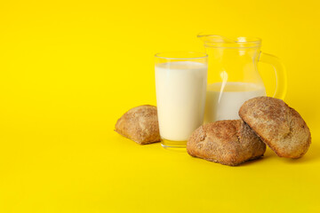 Fresh baked buns and milk on yellow background