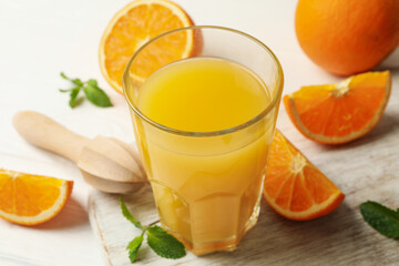 Obraz na płótnie Canvas Board with glass of orange juice, oranges and juicer on wooden background