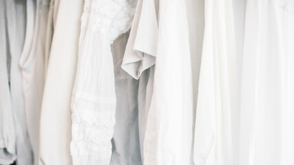 Different white clothes hanging on rail on blue background.