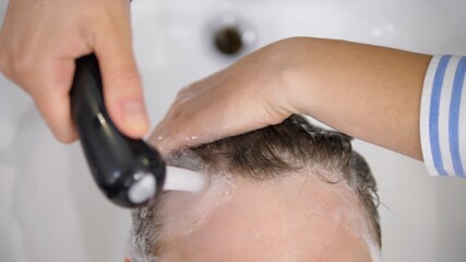 Close up of hands washing hair in hair salon. Beauty and self care concept.