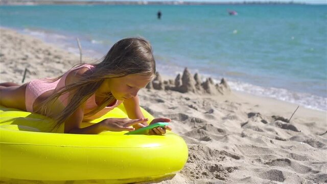 Adorable girl on inflatable air mattress on the beach