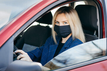 Young girl in black mask sitting in a car, protective mask against coronavirus, driver on a city street during a coronavirus outbreak