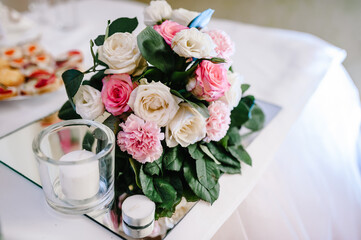 Big bouquet of fresh flowers, pink, white roses and greenery, candles. Wedding flowers, bridal bouquet closeup. Home decor on table, vintage style. Decoration objects.