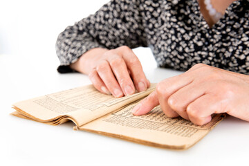 The old man is flipping through an old yellowed book