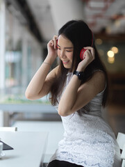 Female teenager listening music with headphone while relaxing in cafe