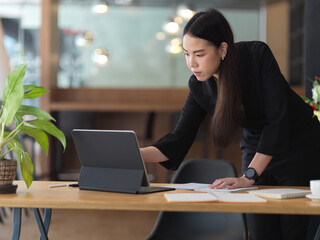 Businesswoman in black suit working with digital tablet on office desk