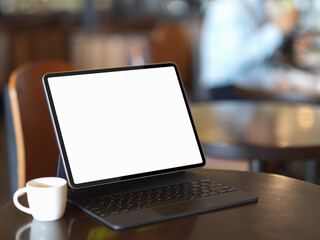 Mock up digital tablet with keyboard and coffee cup on coffee table