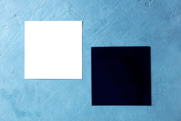 A mockup for two square cards, white and black, with a place for text, shot from the top on a blue background