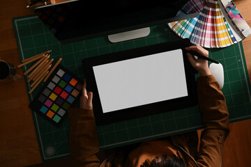 Female graphic designer working with mock up tablet and designer supplies on computer desk