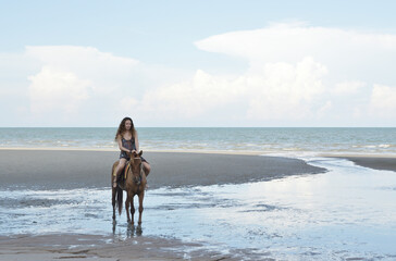 Woman riding horse on the beach over sea and sky, soft tone, Business summer holiday and travel concept