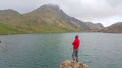 a man in a red coat and by the lake
