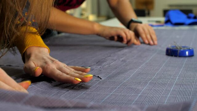 Female hands cut the fabric with scissors, close-up. Female tailor in a sewing workshop. Sewing workshop work. Repair and sewing of clothes. Atelier workers 