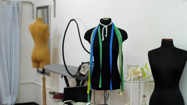 Several headless mannequins stand in a sewing workshop. Centimeters ribbons or measuring tape hanging on the mannequin body. Sewing atelier work