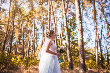 happy bride with a bouquet is walking the green park