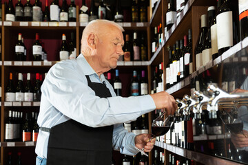 senior man professional sommelier pouring wine from wine column
