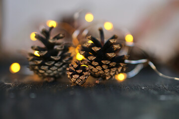 Christmas cones. Yellow garlands. New Year's lights. Holiday image with Christmas golden garland lights and pine cones over wooden background