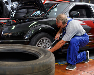 Mechanic technician installing car wheel after repair of balancing at service station..
