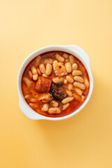 typical spanish dish fabada, beands with smoked sausages and meat on white dish