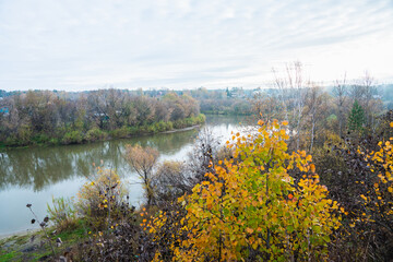 Autumn morning in rainy day with river and forest on the shores. Autumn landscape.