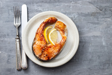 fried salmon with lemon on the dish on ceramic background