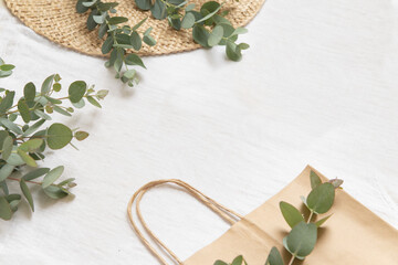 Bambool toothbrush on wood plate and tote bag. Leaves of eucalyptus on a light fabriс background.