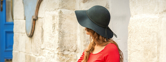 Beautiful young caucasian woman wearing black hat and red dress