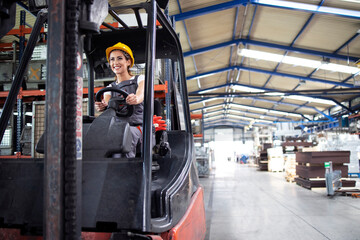 Professional female industrial driver operating forklift machine in factory's hall. © littlewolf1989