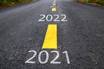 Fototapeta premium Number of 2021 to 2025 on asphalt road with yellow line marking on road surface. Happy new year concept and productive idea