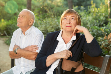 Elderly man and woman offended by each other sitting on bench in park