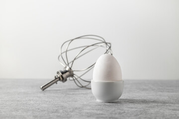 composition of white egg in a stand and a whisk for a kitchen machine
