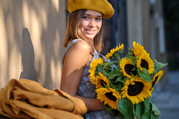 Street portrait of a beautiful young woman  holding a sunflower