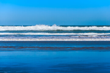 Big powerful ocean waves hitting sandy shore of Ninety Mile Beach, North Island, New Zealand
