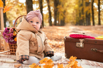 a small child is sitting in an autumn Park in a beautiful turban