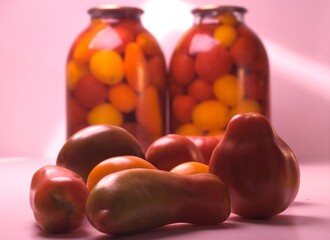 a bunch of tomatoes of different shapes and shades, against the background of two cans of canned tomatoes