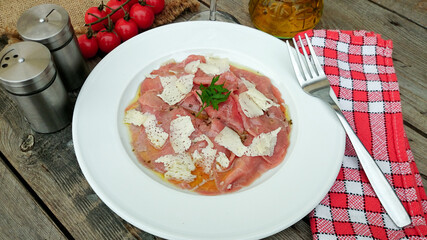 assiette de carpaccio de boeuf et parmesan sur une table en bois