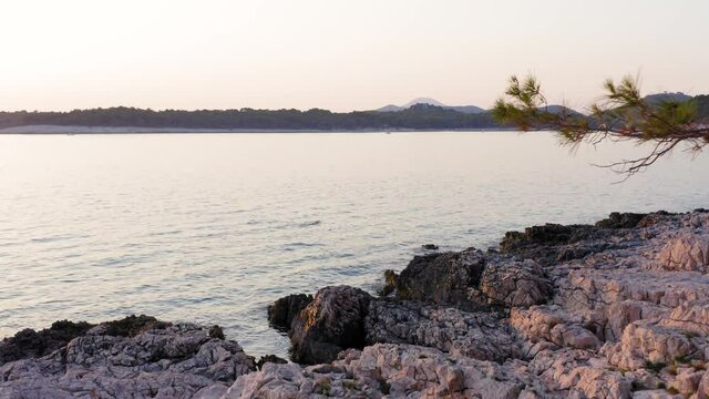 Relaxing snorkling on calm water next to purply rocky shore on sunset
