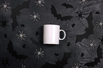 Halloween holiday white coffee mug with decorative bats and spiders on black table