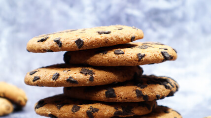 American chocolate chip cookies stacked on top of each other on a beautiful gray marble background. Traditional rounded crunchy dough with chocolate chips. Bakery. Delicious dessert, pastries.