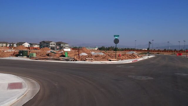 Empty 4 way intersection road with housing construction on all sides and pallets of building materials.