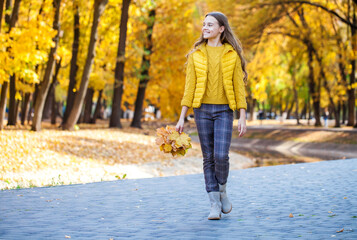 Blonde teenage girl posing in autumn park