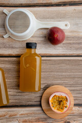 Fresh passion fruit juice in bottle with passion fruits on wood background.