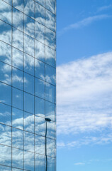 Fototapeta na wymiar Glass facade reflects the blue sky and white clouds