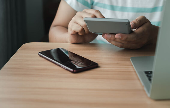 Business & Finance concept. Close up hand of young Asian man wear white shirt ongoing to calculate home loan mortgage to summary expense payment or accounting with using smartphone on office deck
