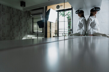 woman in white clothes wear the VR machine sit on the long table.
