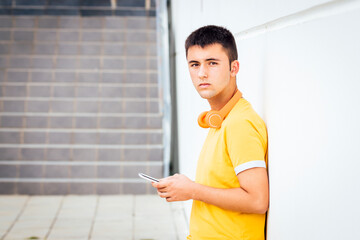 Teenager waiting leaning on wall with yellow t-shirt